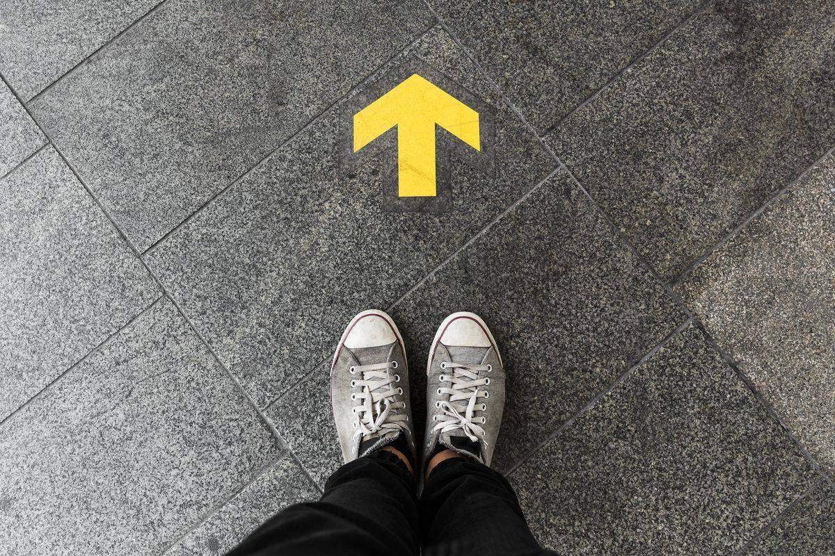 Standing on a pavement arrow pointing forward: choosing a direction before moving