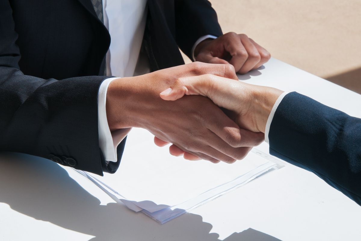 A handshake across a table over a signed document, the offer agreed